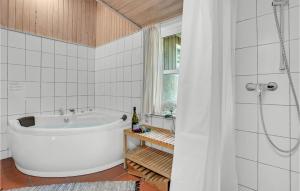 a white bathroom with a tub and a window at Holiday Home Rylen Rømø Xi in Rømø Kirkeby