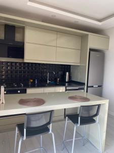 a kitchen with a white counter and two chairs at Antalya Havalimanına Yakın Havuzlu 1+1 Lux Daire in Antalya +2 photos