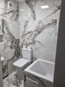 a bathroom with a white toilet and a marble wall at Stylish London Apartment & Free Parking in London