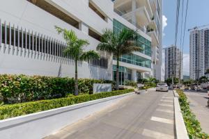 a street in front of a building with palm trees at Apartamentos Cartagena Marbella Suite in Cartagena de Indias