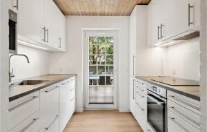 una cucina con mobili bianchi e soffitto in legno di Gorgeous Home In Rømø With Sauna a Rømø Kirkeby