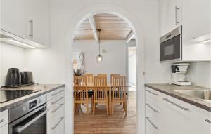 una cucina con mobili bianchi e un tavolo con sedie di Gorgeous Home In Rømø With Sauna a Rømø Kirkeby Altre 26 foto