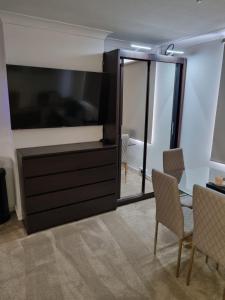 a living room with a large television and a table and chairs at Stylish London Apartment & Free Parking in London