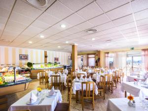 Un comedor con mesas y sillas blancas y un restaurante. en BelleVue Aquarius, en Puerto del Carmen