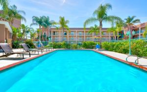 a swimming pool with chairs and a building at Cortona Inn and Suites Anaheim Resort in Anaheim