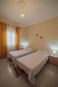 a bedroom with two beds and a window at Home Sweet Home A Quiet,Spacious Two-Bedroom house in Dërmish