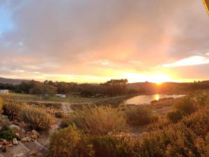 a sunset over a river with the sun setting at Kleinwatervalplaas Farm Stay Accomodation in Caledon +5 photos