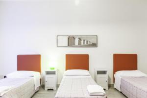 Habitación con 3 camas y una foto en la pared. en IN FIERA 5 appartmento, en Bolonia