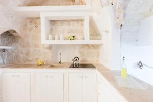 eine weiße Küche mit weißen Schränken und einem Waschbecken in der Unterkunft Casa Zio Piero in Ostuni