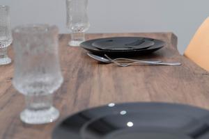 a wooden table with a black plate and glasses on it at Spacious & Relaxing Home with Free Parking in Vlorë