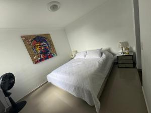 a bedroom with a bed with a painting on the wall at Espectacular Apartamento Ibagué in Ibagué +27 photos