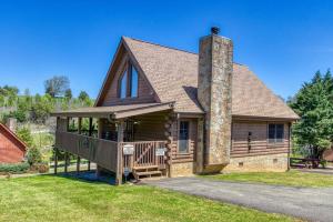 una casa de madera con porche y chimenea en Minutes to Dollywood &The Island in Pigeon Forge Hot tubOutdoor FirepitGas GrillIndoor Fireplace, en Sevierville