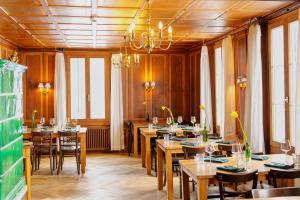 a restaurant with wooden tables and chairs and windows at Pilgerhaus Maria-Rickenbach - Anreise nur via Luftseilbahn möglich in Dallenwil