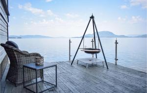 a porch with a swing and a boat on the water at Lovely Home In Skånevik in Skånevik