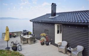 a house with a deck with a table and chairs at Lovely Home In Skånevik in Skånevik +17 photos