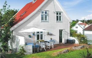 a white house with a table and an umbrella at Holiday Home Skudeneshavn Kvednadalen in Skudeneshavn
