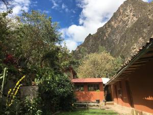 a building with a mountain in the background with trees at HOSTEL INKA PACCHA - cascada inka in Ollantaytambo