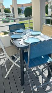 een blauwe tafel en stoelen op een terras met glazen bij Entre Golf et Mer in Pornic