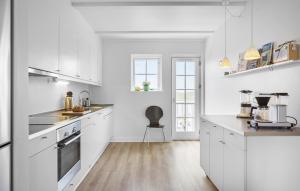 a kitchen with white cabinets and a chair in it at Pet Friendly Apartment In Bagenkop in Bagenkop
