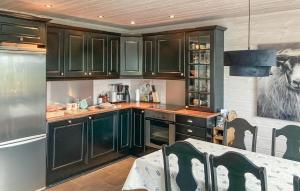a kitchen with dark green cabinets and a cow painting on the wall at 3 Bedroom Beautiful Home In Åseral in Åseral