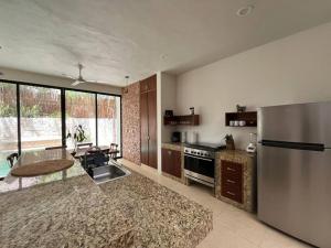 Una cocina con refrigerador de acero inoxidable y una mesa. en Jungle Retreat Luxury Villa with Pool inTulum, en Tulum