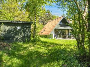 a small house in a field next to a shed at 4 person holiday home in Ebeltoft-By Traum in Ebeltoft