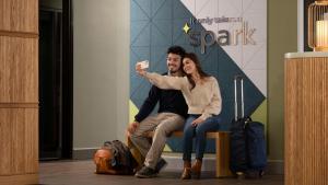 休斯顿Spark By Hilton Houston Bush Intercontinental Airport的一男一女坐在长凳上，手里拿着 Wii 遥控器
