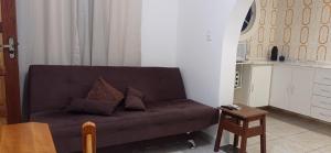 a living room with a brown couch and a table at Casa temporada no Indaiá com wi-fi e churrasqueira in Caraguatatuba