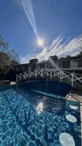 a swimming pool with a white bridge and blue water at Hotel La Fontaine in La Lucila del Mar