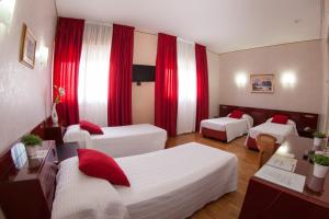 a hotel room with three beds and red curtains at Hotel Master in Albignasego