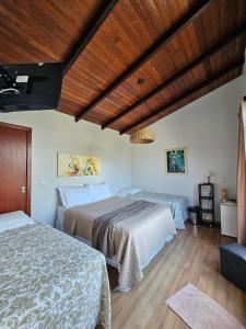 a bedroom with two beds and a wooden ceiling at Casa da Flôr GuestHouse, Praia Grande, Beto Carrero in Penha