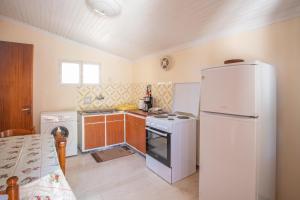a kitchen with a white refrigerator and a stove at GAIA The Cottage House in Nydri