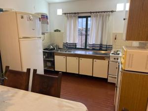 a kitchen with a white refrigerator and a sink at Casa de Beto Estancia Vieja in Estancia Vieja