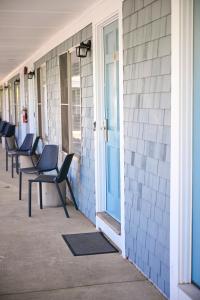 a row of chairs sitting on the side of a building at Endless Dunes, A Modern Motel in Eastham