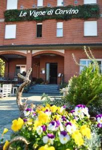 un bâtiment en briques rouges avec des fleurs devant lui dans l'établissement Hotel Le Vigne di Corvino, à Casteggio