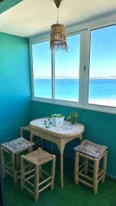 - une table et deux tabourets dans une pièce avec fenêtres dans l'établissement Cozy Appartement Next to the Beach, à Tanger