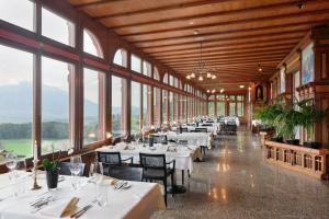 a dining room with tables and chairs and windows at Jugendstilhotel Paxmontana in Sachseln