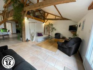a living room with two black chairs and a tv at Grange rénovée avec piscine privative - 4 ch, jardin clos, à 7 km d'Indian Forest - FR-1-426-304 in Le Champ-Saint-Père