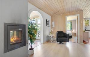 a living room with a fireplace and a chair at Awesome Home In Løgstør With Sauna in Trend