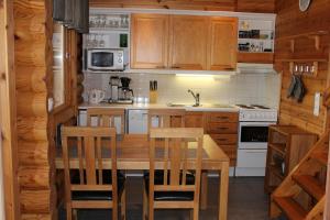 una cocina con armarios de madera y una mesa y sillas de madera. en Rinnetupa Apartment, en Tahkovuori