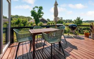 une terrasse en bois avec une table, des chaises et un parasol dans l'établissement Holiday Home Træløbervej Tranekær Ii, à Lokkeby