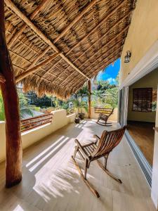 a room with two chairs and a thatched roof at Hotel & Suites Oasis Bacalar in Bacalar
