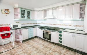 a kitchen with white cabinets and a red chair in it at Nice Apartment In Santa Pola in Santa Pola