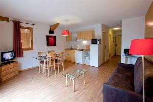 a living room with a couch and a kitchen at Résidence Orelle 3 vallées by AltiResid in Orelle