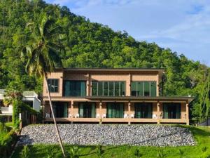 a house with a palm tree in front of a mountain at Tiger House River Kwai in Ban Tha Thong Mon