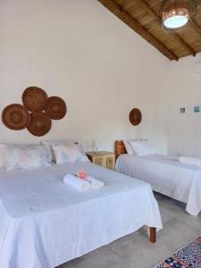 two beds in a room with white walls at Timborana Suítes in Trancoso