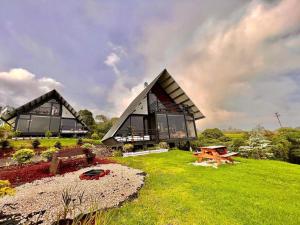 a large house with glass windows on a green field at Cabañas de Montaña Magia del Poás in Poás