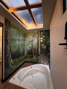 a bath tub in a bathroom with a painting on the wall at Cabañas de Montaña Magia del Poás in Poás