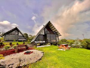 a large house with glass windows on a green field at Cabañas de Montaña Magia del Poás in Poás