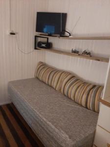 a bed in a room with a tv on the wall at Pé na areia, casa na praia de frente para o mar in Florianópolis +49 photos